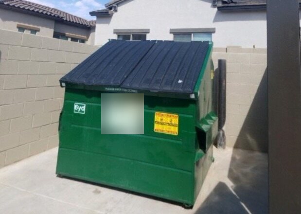 A clean dumpster enclosure after service, the dumpster closed and the ground swept