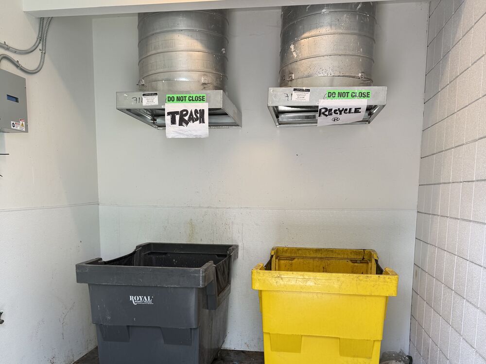 A chute room with a trash chute and a recycling chute, each labeled, above its own empty cart