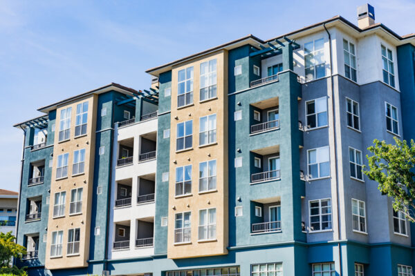 Colorful apartment building with blue, yellow, and beige facades and balconies under a clear sky.